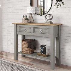 a grey console table with two drawers and a mirror on the wall in front of it