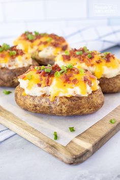 baked potatoes with cheese and green onions on a cutting board