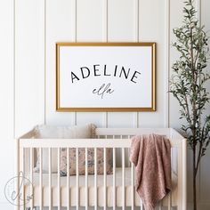 a baby's crib in front of a white wall with an adeline sign above it