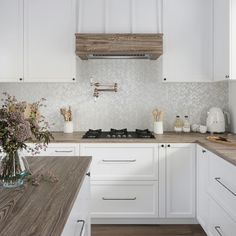 a kitchen with white cabinets and wooden counter tops, along with a vase filled with flowers