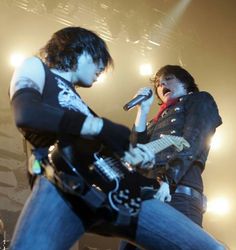 two people on stage with guitars and microphones