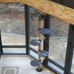 a cat tree in the corner of a room next to a glass door and window