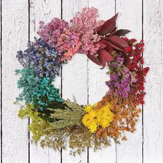 a wreath made out of dried flowers sitting on top of a white wooden table next to a wall