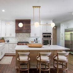 a large kitchen with white cabinets and wooden flooring, along with an island in the middle