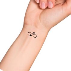 a woman's arm with a small tattoo on it that has a dog paw and heart