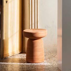 a small wooden stool sitting on top of a tile floor next to a door way