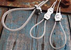 two metal wires connected to each other on top of a wooden table with rusted boards