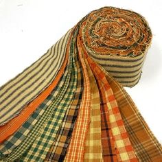 a pile of different colored plaid fabric on a white surface