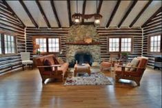 a large living room with wood floors and stone fireplace