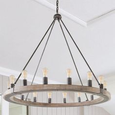 a wooden chandelier hanging from the ceiling in a room with white walls and wood paneling