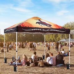 a group of people sitting under a tent on top of a field