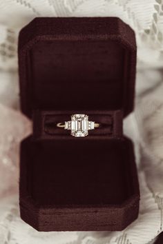 an engagement ring in a velvet box on a lace tablecloth with the diamond setting