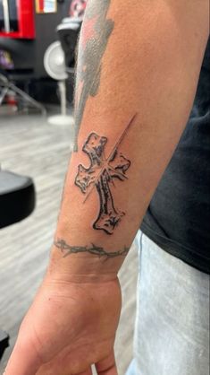 a person with a tattoo on their arm holding a knife and cross in his hand