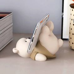 a small white bear holding a laptop on its back paws at it's side