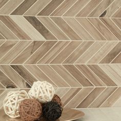 two balls of yarn sit on a plate in front of a chevron tile wall