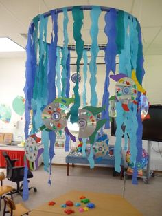 a room filled with lots of blue and green streamers hanging from the ceiling next to a table