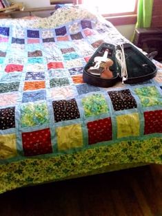 a bed with a colorful quilt on it and a pair of shoes sitting on the pillow