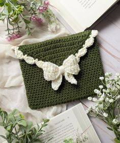 a crocheted bookmark with a bow on it next to flowers and an open book