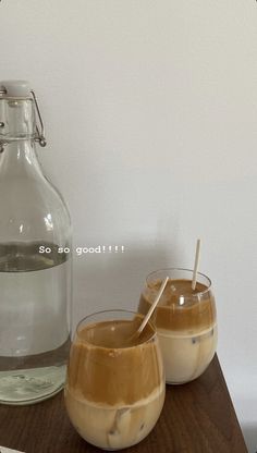 two glasses filled with liquid sitting on top of a wooden table