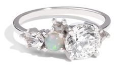 an opal and diamond ring with three stones in the center, on a white background