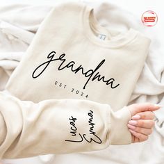 a woman's hand holding onto a shirt with the word grandma on it