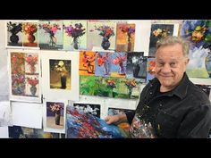 an older man is holding up some art work in front of his face and looking at the camera