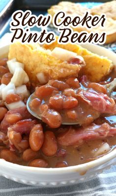 slow cooker pinto beans in a white bowl with cornbreads on the side