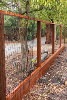 a wooden fence with wire around it and a tree in the back ground behind it