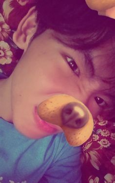 a young boy laying on top of a bed with a stuffed animal in his mouth