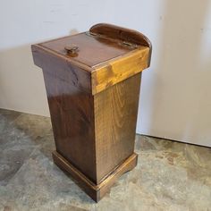 a wooden box sitting on top of a floor next to a white wall and cement floor