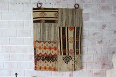 a wall hanging made out of old rugs on a brick wall next to a sink