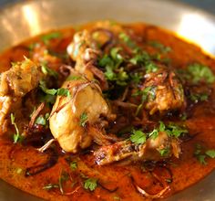 a silver plate topped with meat covered in sauce and garnished with cilantro