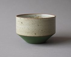 a white and green bowl sitting on top of a gray table next to a wall