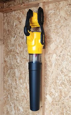 a yellow and black object mounted to the side of a wall in a room with plywood