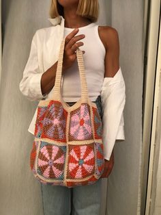 a woman holding a crocheted purse in front of her face and looking at the camera