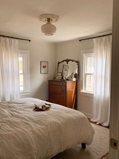 a bedroom with a bed, dresser and two windows