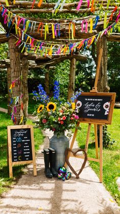 an outdoor ceremony with colorful streamers and flowers on the grass, next to a chalkboard sign