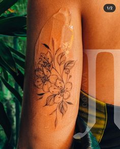 a woman's arm with flowers on it and leaves around the arm, in front of her