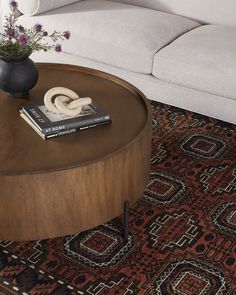 a coffee table with a book on it in front of a white couch and rug