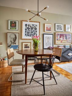 a dining room table with chairs and pictures on the wall