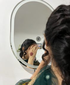 a woman is looking at her reflection in the mirror