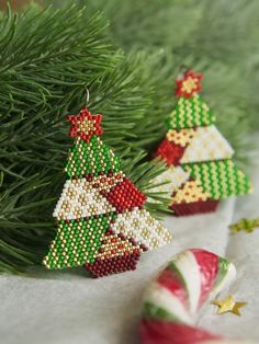 three beaded christmas trees sitting on top of a table next to candy canes