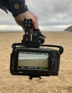 a person is holding a camera on the beach