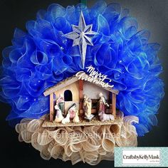 a nativity ornament hanging on a wall with blue tulle around it