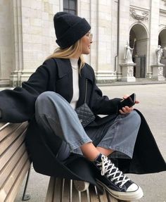 a woman sitting on top of a wooden bench