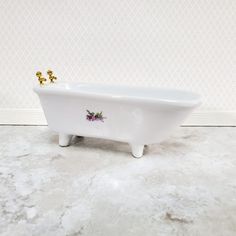 a white bath tub sitting on top of a floor next to a wall with flowers