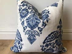 a blue and white pillow sitting on top of a wooden floor next to a wall