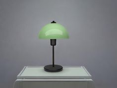 a green lamp sitting on top of a white table next to a gray wall and floor