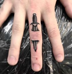 a person with a knife tattoo on their ring finger