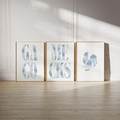 three framed art pieces sitting on top of a wooden floor